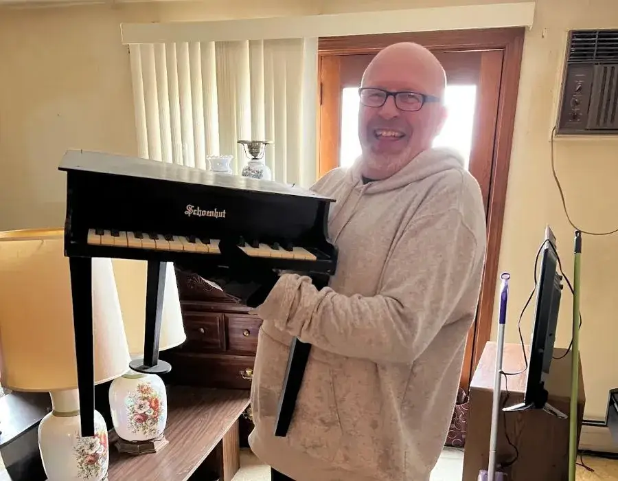 Man holding small piano, smiling happily.
